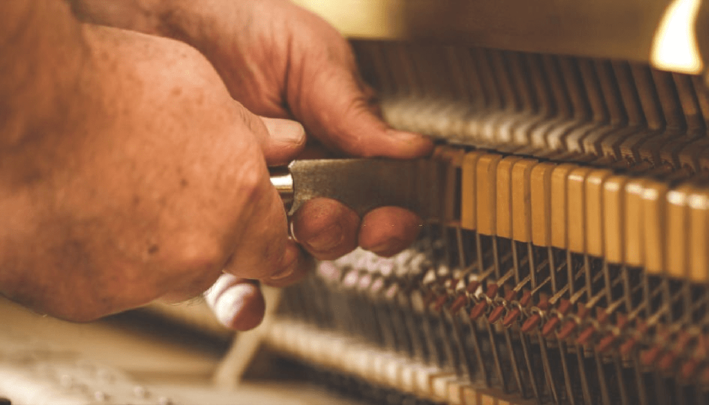 Repairing a piano with a specialized tool by an expert technician from Osborne and Everett